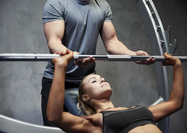 Blonde Frau wird von einem Personal Trainer gesichert